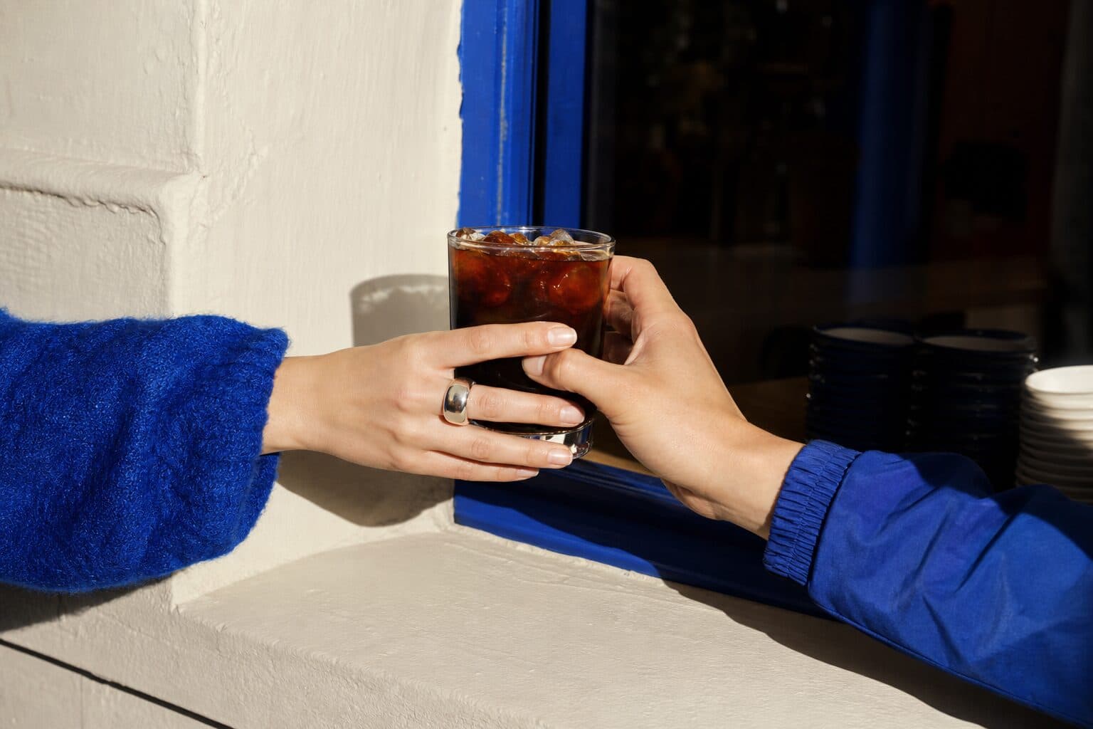 An iced americano passed across the window sill, blue cups stacked inside
